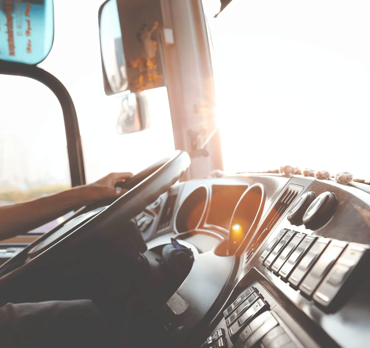 A hand on a steering wheel in the cab of a truck