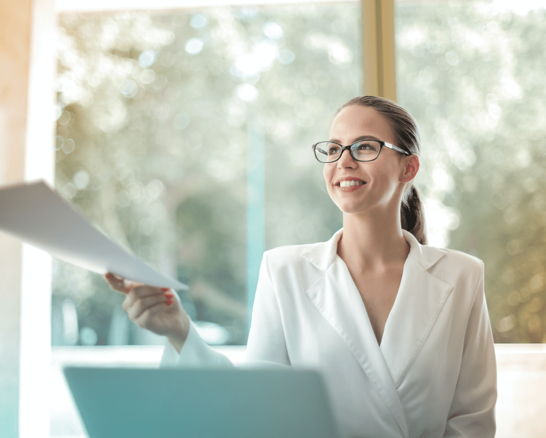 Woman in blazer handing papers to someone off-screen