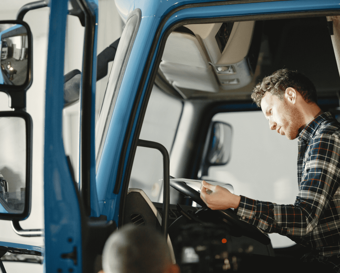 Driver sitting in cab of truck reading a booklet