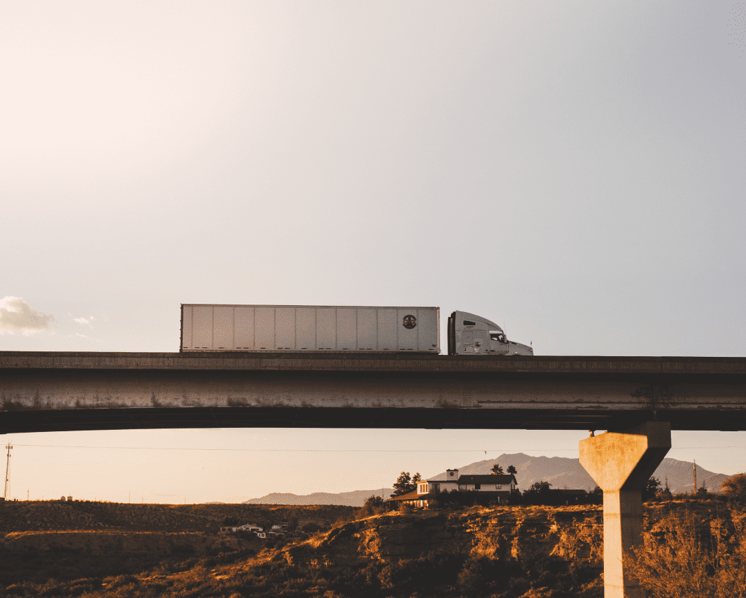 Truck with trailer drivers over raised road with horizon in background