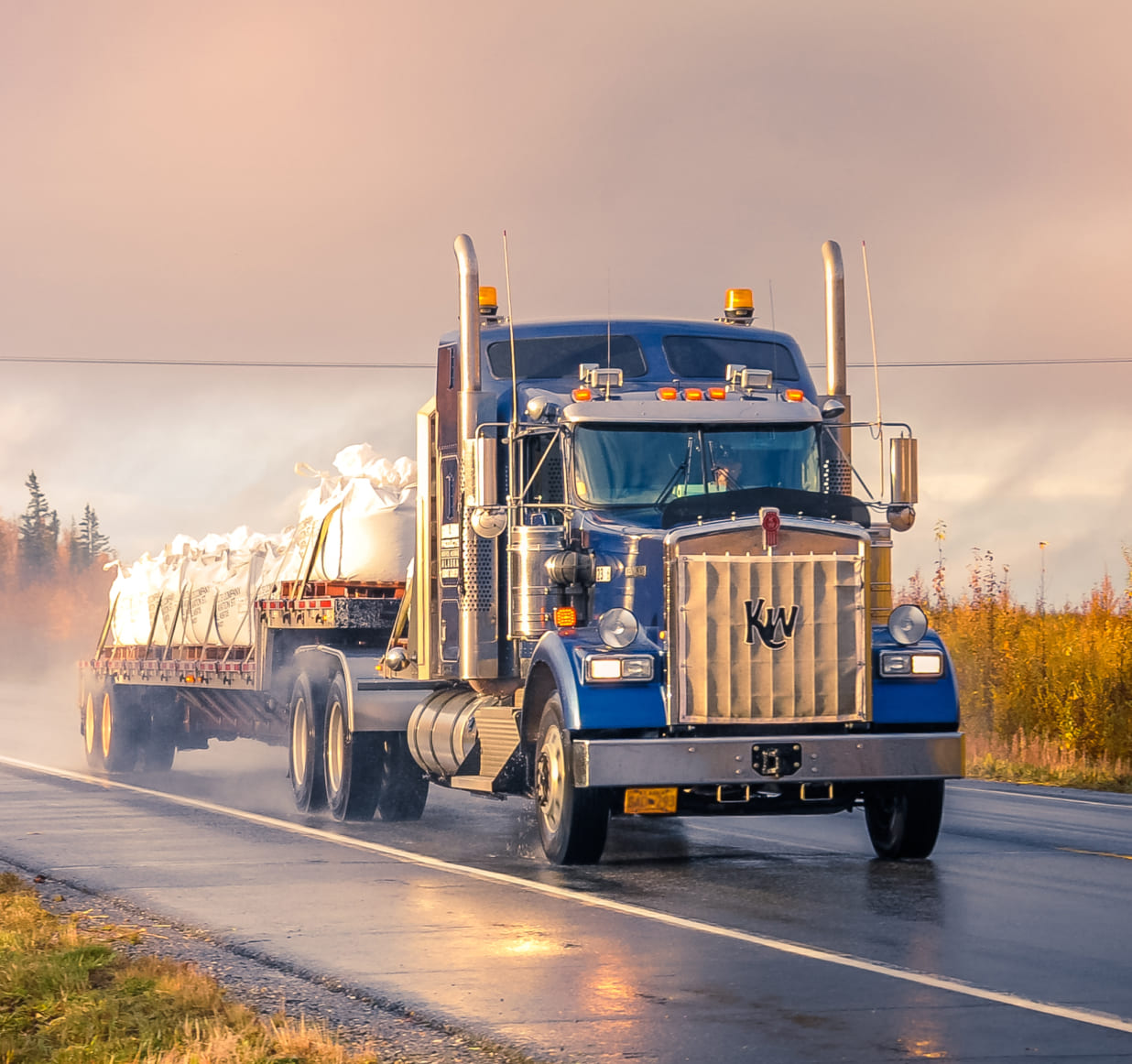 Flatbed truck driving through the rain at sunset